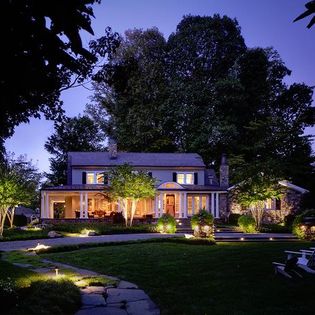 Front facade of a home with exterior lighting in the landscape